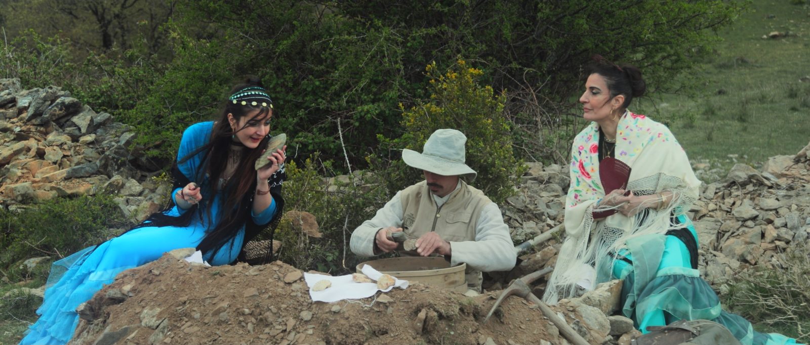 Two sirens beside the fossil hunter, who sifts the soil of his dig